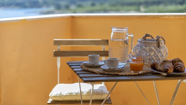 A breakfast setup on a balcony with a view of hills. - Dea Fertilia. Terraced house few steps from the sea. (Fertilia)