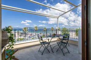 Ein Balkon mit Tisch und Stühlen mit Blick auf Strand und Stadtlandschaft.