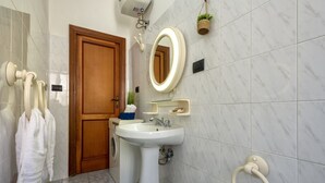 Une salle de bain avec un lavabo, un miroir, un porte-serviettes et une porte.