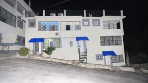 A two-story building with a flat facade, multiple windows, and a gated entrance.