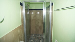 A bathroom with a glass-enclosed shower, tiled walls, and a visible toilet.