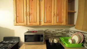 A kitchen with wooden cabinets, a gas stove, a microwave, and a dish drying rack.
