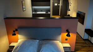 Un dormitorio con cama, lámparas de noche, escritorio integrado y espejo.