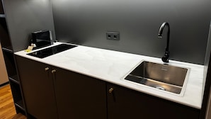A modern kitchen with a stainless steel sink, a black faucet, and a built-in range hood. - ipartment Leverkusen @HOME by Best Western (Leverkusen)