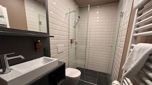 A modern bathroom with a glass-enclosed shower, a white sink, and a toilet. - ipartment Leverkusen @HOME by Best Western (Leverkusen)