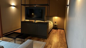 Un dormitorio moderno con cama, mesita de noche y televisor montado en la pared.
