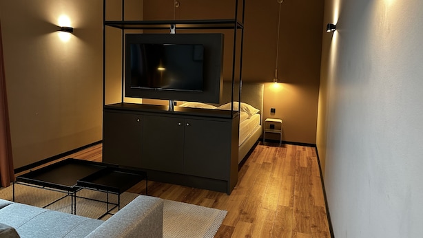 A modern bedroom with a bed, bedside table, and a TV mounted on a wall. - ipartment Leverkusen @HOME by Best Western (Leverkusen)