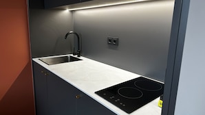 A modern kitchen with a stainless steel sink, a black induction cooktop, and a single electrical outlet. - ipartment Leverkusen @HOME by Best Western (Leverkusen)