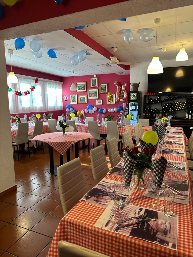 Un restaurant avec des nappes à carreaux rouges et blancs, des ballons et des tableaux encadrés accrochés aux murs.