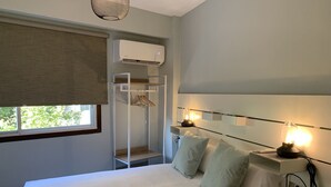 A hotel room with a bed, bedside lamps, a wardrobe, and an air conditioning unit. - Home SEA&DREAMS Beach (Calp)