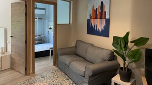A modern living room with a grey sofa, a large potted plant, and a cityscape painting on the wall. - Home SEA&DREAMS Beach (Calp)
