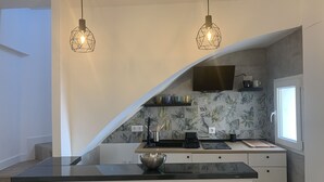 Una cocina moderna con una isla curva, estufa a gas y microondas. Dos lámparas colgantes iluminan la isla.