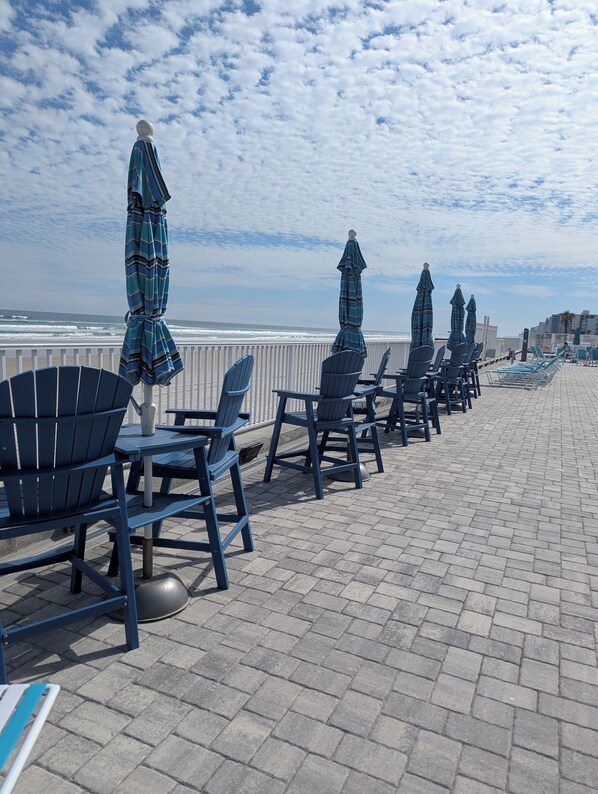 A beachside seating area with chairs and umbrellas, overlooking the ocean.