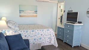 A bedroom with a bed, a sofa, a dresser, and a TV.