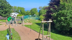 Un parque infantil con una estructura de madera para escalar, un tobogán y un área cercada.