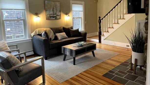 A living room with a sofa, coffee table, and a staircase. - Charming Cottage in Jamestown (Jamestown)