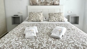 Un lit bien fait, avec une literie à motifs et deux serviettes pliées posées sur le lit.