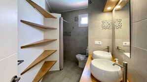 Une salle de bain moderne avec deux lavabos, des étagères en bois, un espace douche et des toilettes.