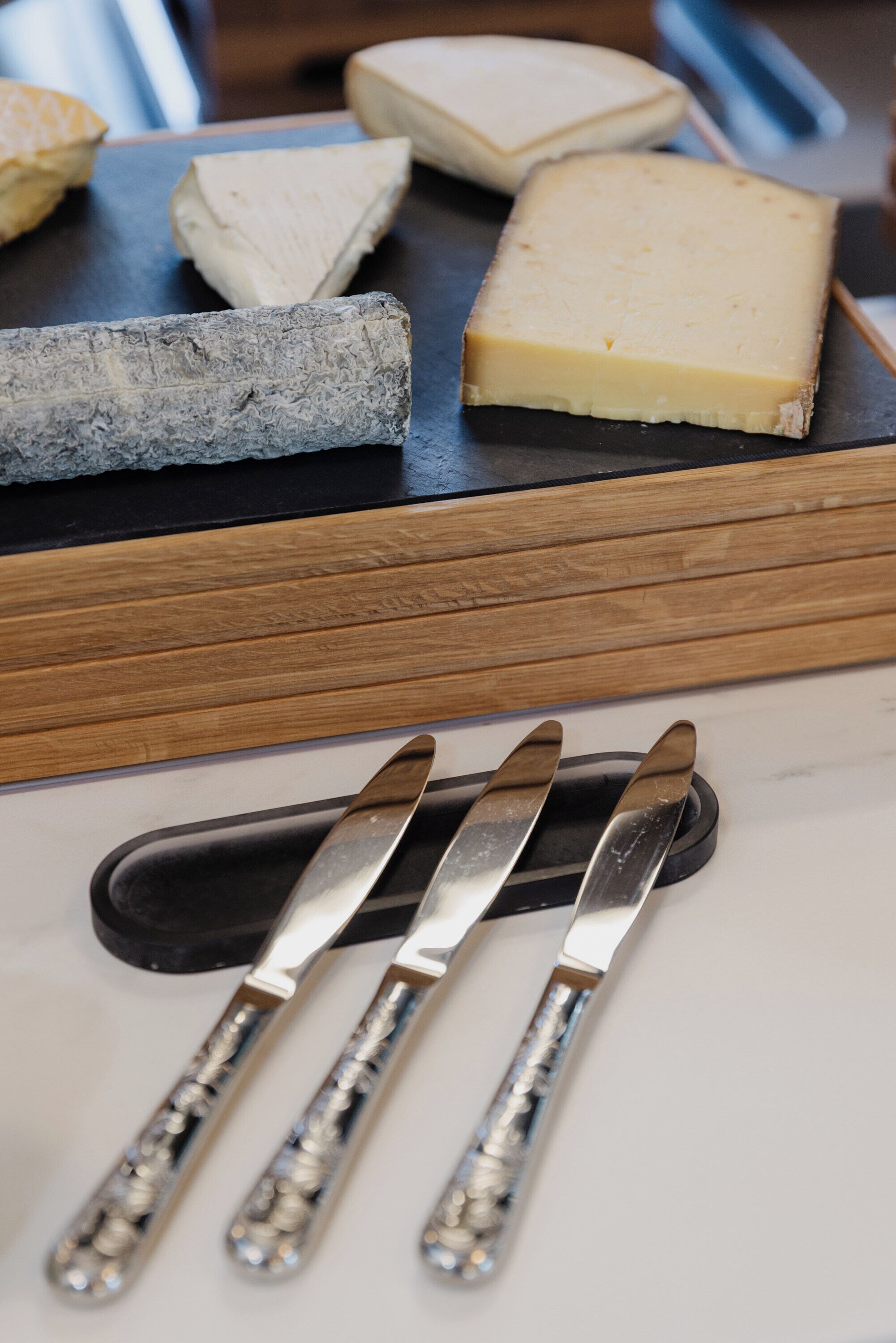 Une sélection de fromages présentée sur une planche en bois, avec un couteau et une fourchette à côté.