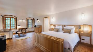 A spacious bedroom with a large bed, wooden headboard, bedside tables, and a desk area.