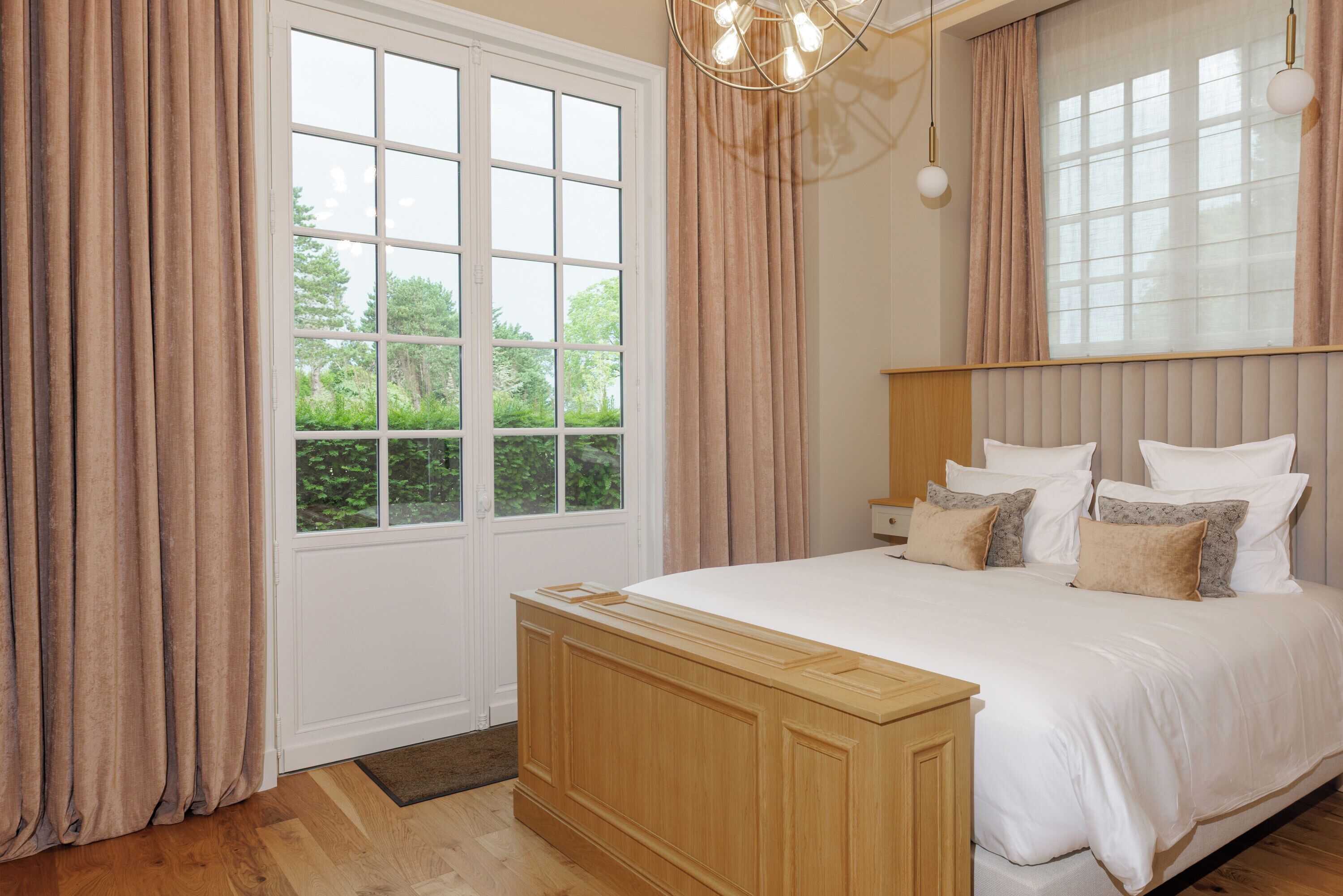 Ein Schlafzimmer mit einem großen Bett, einem Holzkopfende und Blick auf Grün.