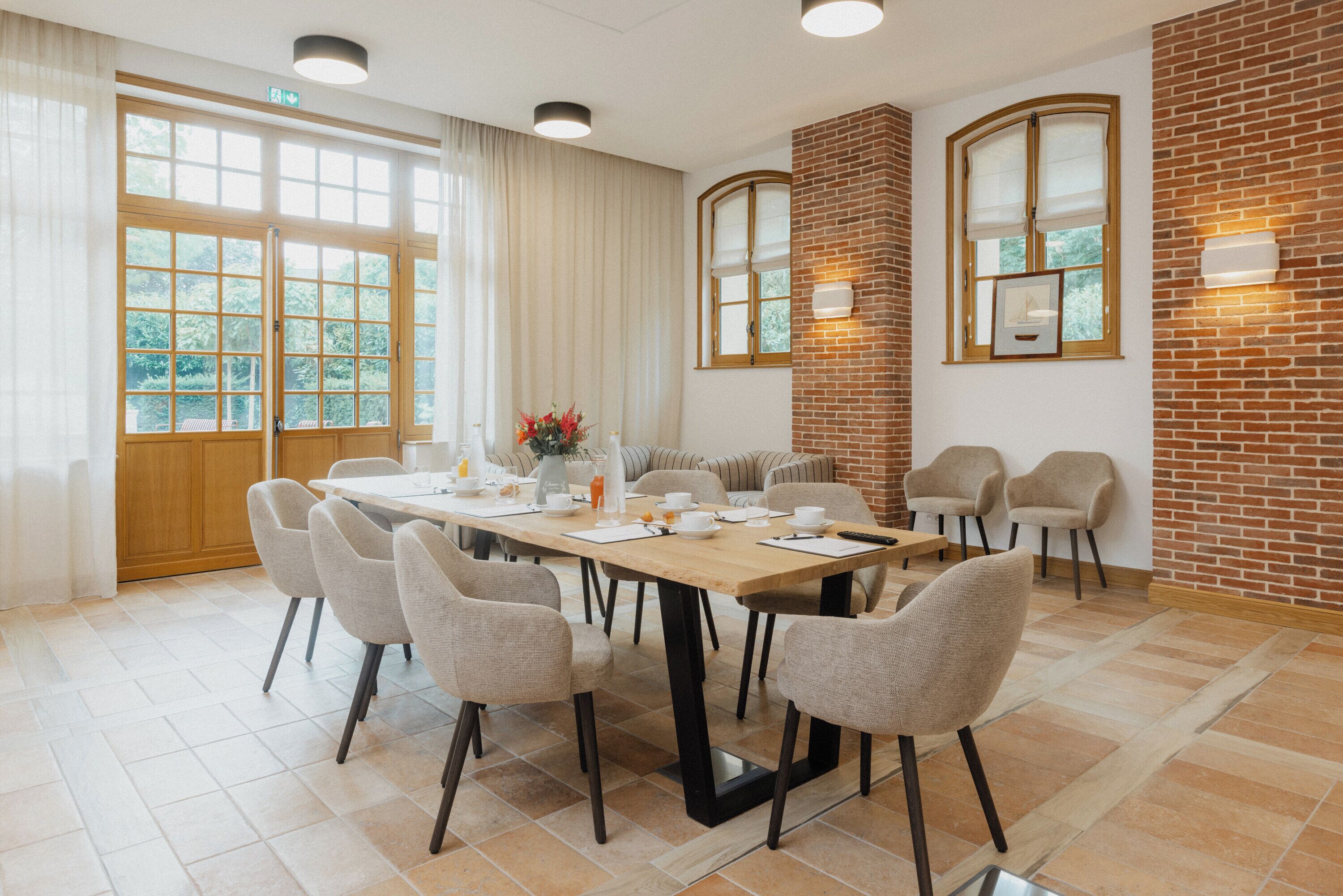 A conference room with a long table, six chairs, and a brick accent wall.