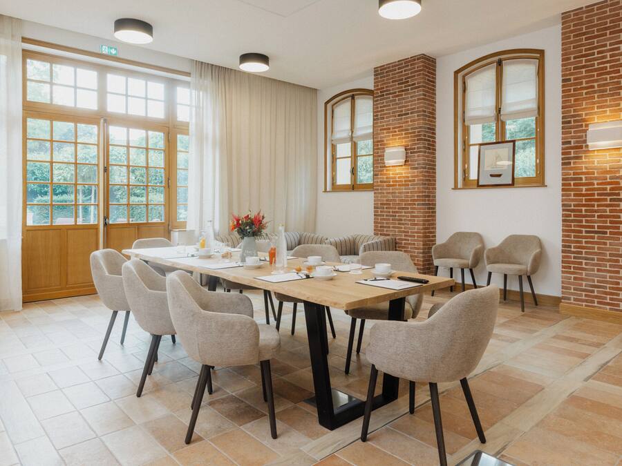 A conference room with a long table, six chairs, and a brick accent wall.