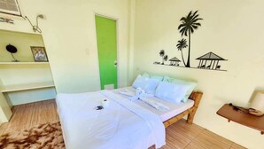 A neatly made bed with a white bedspread and pillows, a wooden floor, a green door, and a wall with a tropical mural. - 8hotel (Bantayan)