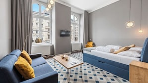 Een moderne hotelkamer met een bank, een bed, een salontafel en een televisie.