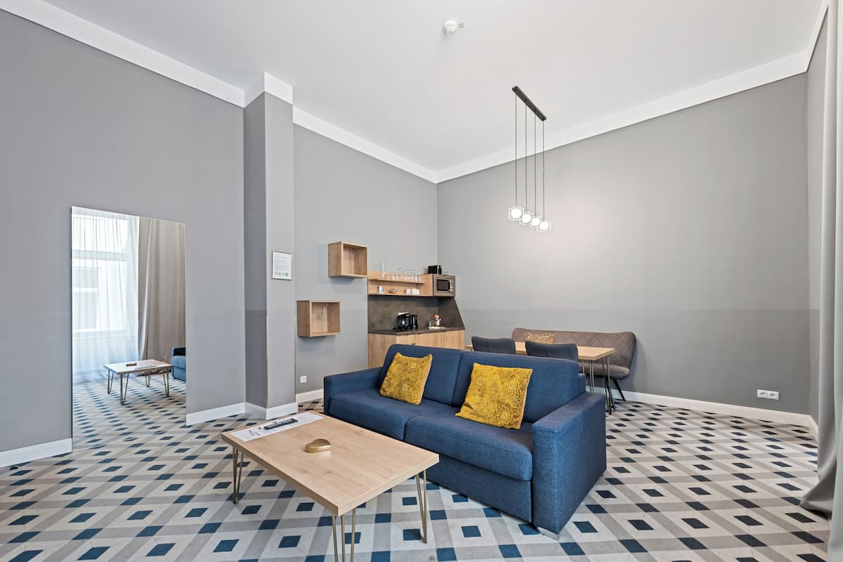 A modern living room with a blue sofa, wooden coffee table, and patterned floor tiles.