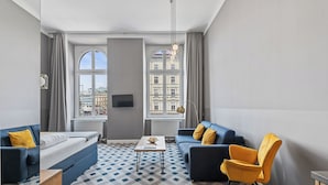 Een moderne woonkamer met een bank, fauteuil en salontafel, grote ramen met uitzicht op de stad, en een kamer met een patroon vloer.
