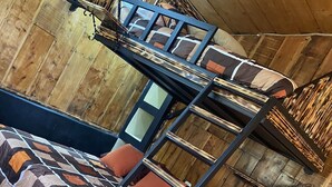 Ein Stockbett mit einem Bettbezug mit geometrischem Muster, Holzwänden und einem gefliesten Boden.