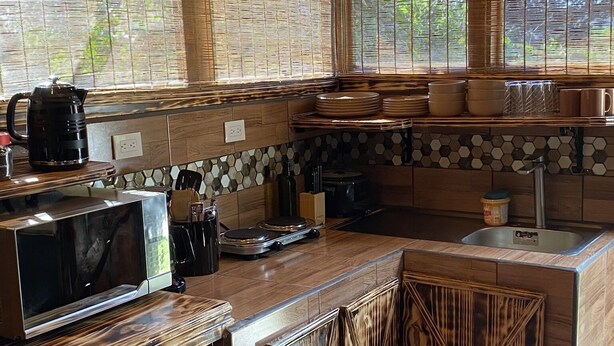 Eine Küche mit Holzschränken, einer Mikrowelle, einer Kaffeemaschine und einem Spülbecken.