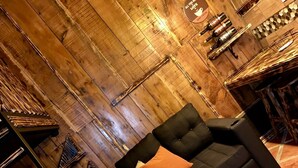 Ein gemütliches Zimmer mit einer schwarzen Couch, einem gemusterten Teppich und Holzwänden.