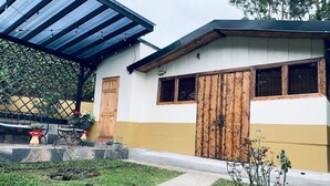 Ein Haus mit überdachter Terrasse, einer Holztür und einem kleinen Garten.
