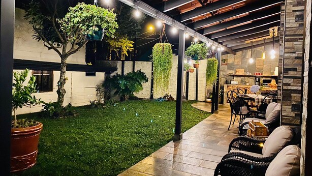 An outdoor patio area with a grassy lawn, hanging plants, and a dining setup with chairs and tables. - The perfect escape to reconnect with nature and yourself.  (Alajuela)