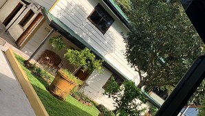 A two-story house with a green roof, a small front porch, and a garden area with potted plants. - The perfect escape to reconnect with nature and yourself.  (Alajuela)