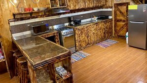 A rustic kitchen with wooden cabinets, a central island, and a stainless steel refrigerator. - The perfect escape to reconnect with nature and yourself.  (Alajuela)