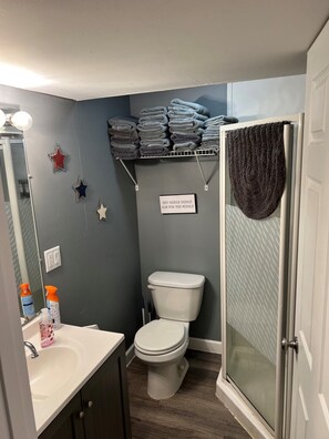 A bathroom with a toilet, sink, and shower. There are star decorations on the wall and a sign that says 'HEY DIDDLE DIDDLE AIM FOR THE MIDDLE'. - Located across the road of West Lake Okoboji. 8 beds. Room for parking trailers (Okoboji)