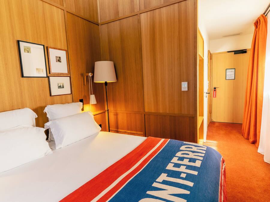 Habitación de hotel con cama, mesita de noche, lámpara y puerta con un letrero.
