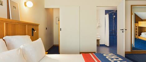 A hotel room with a bed, a wardrobe, a shower area, and a bathroom.