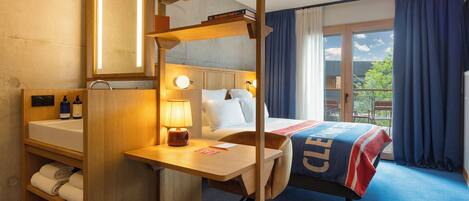 Une chambre d’hôtel avec un lit, un bureau doté d’une lampe, une bibliothèque et une vue sur l’extérieur.