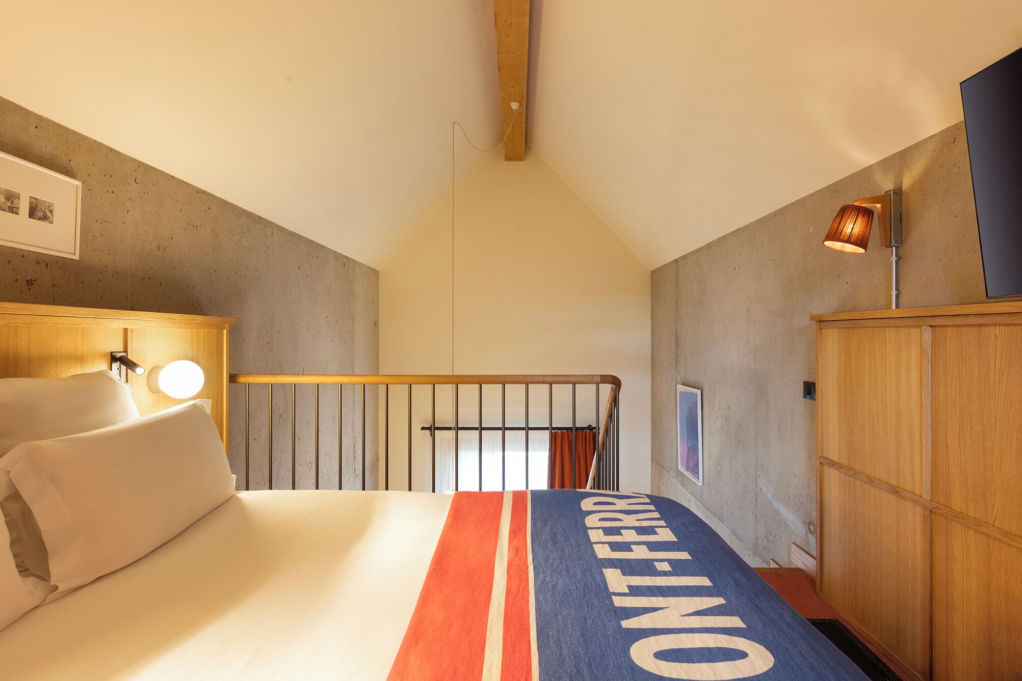 A hotel room with a bed, a wooden headboard, a nightstand, a lamp, and a wardrobe.
