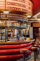 Uma área de bar com várias garrafas de bebidas e uma seleção de torneiras de chopp.