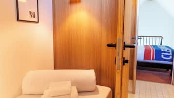 Un dormitorio con cama, armario de madera, un cuadro en la pared y un baño visible a través de una puerta abierta.