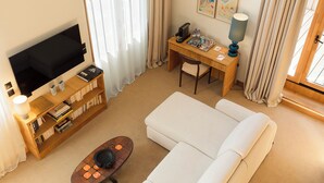 A modern living room with a flat-screen TV, a bookshelf, a coffee table, a sofa, and a desk with a lamp. - GRAND MESS Clermont-Ferrand (Clermont-Ferrand)