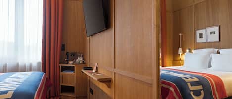 A hotel room with a bed, a desk, a television, and a mirror.