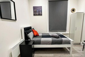 A bedroom with a bed, a window, a wardrobe, and a picture on the wall. - Studio Flat in Ealing Broadway (London)