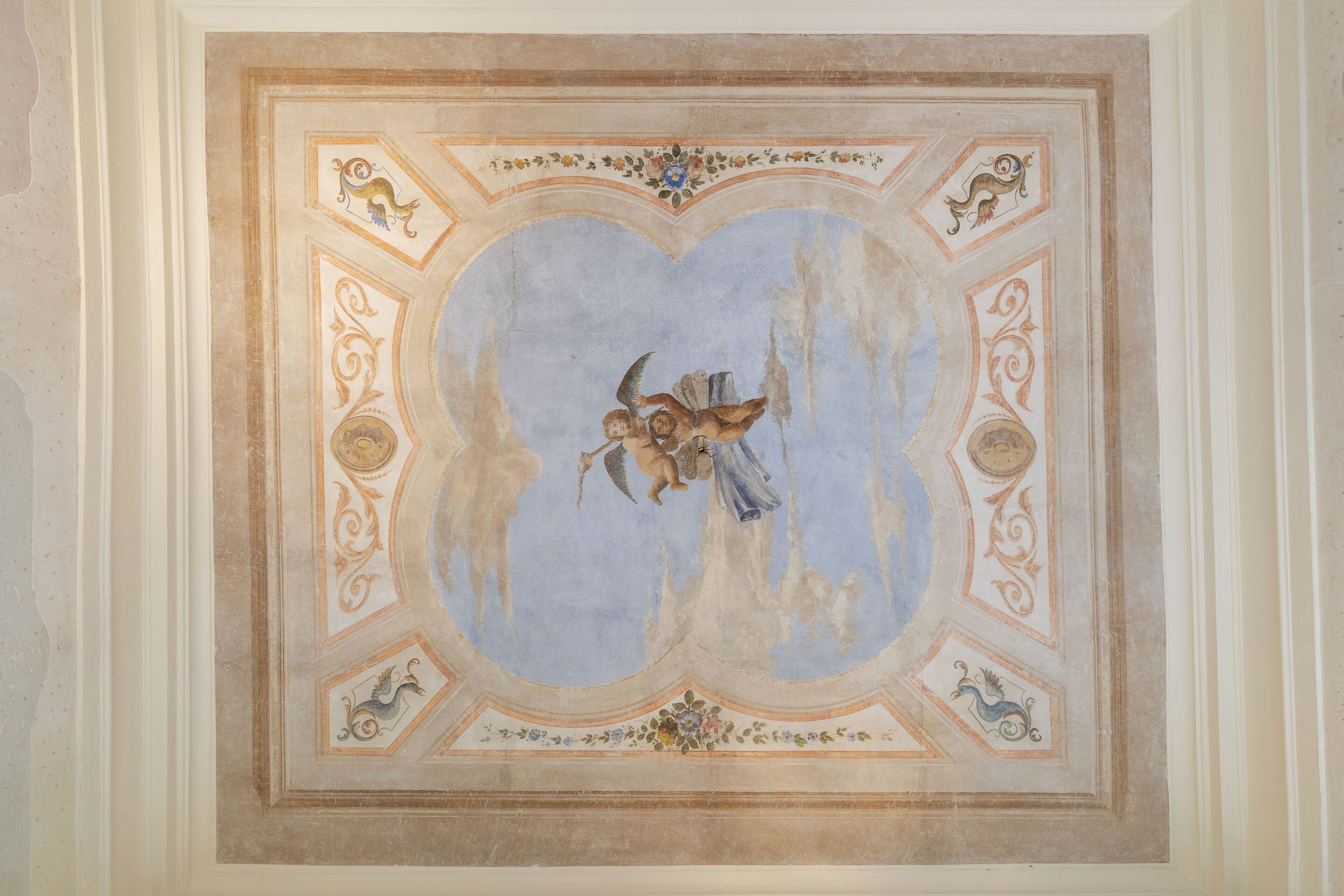 A ceiling with a central fresco of an angel and cherubs, surrounded by ornate decorative elements.