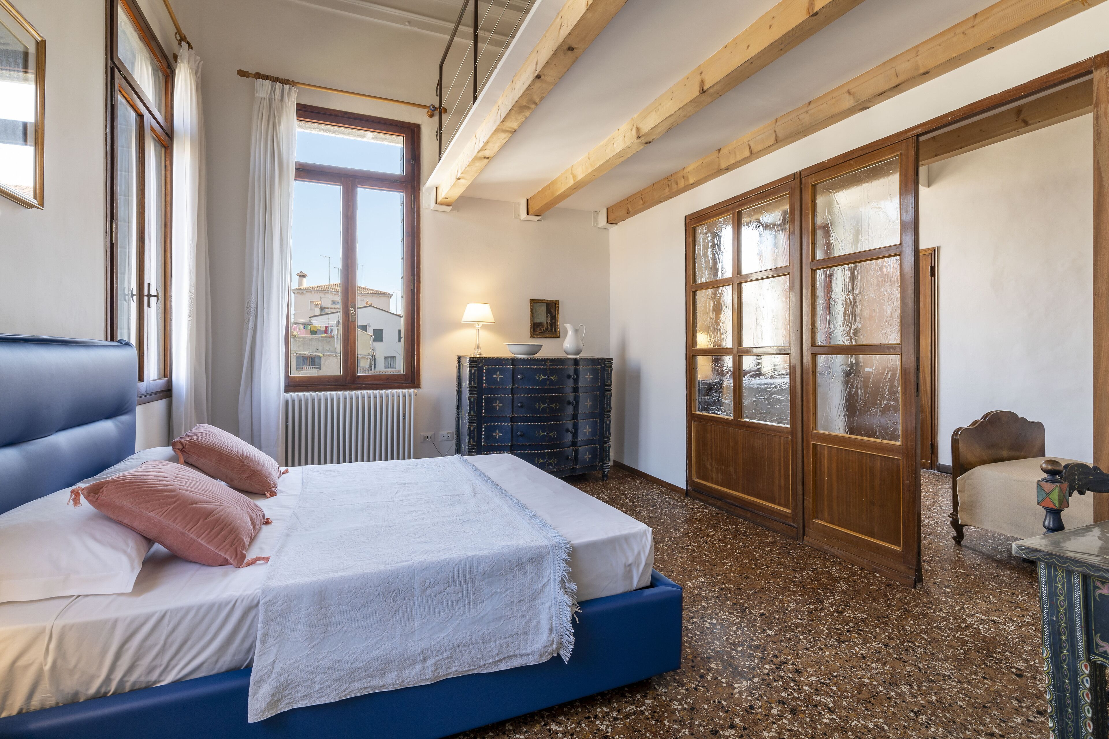 A bedroom with a bed, a dresser, a chair, and a window with curtains.